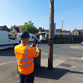 Surveying work is being completed on a road and a person is using a tablet.